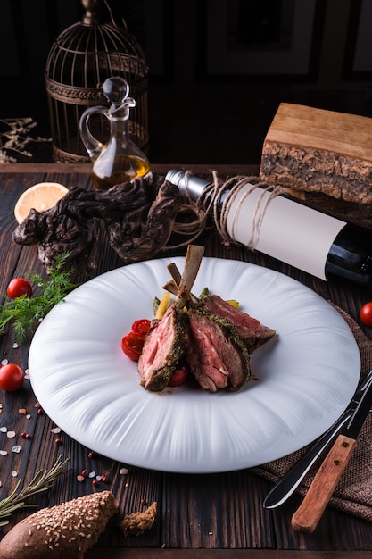 Lamb rack with provencal herbs on a large white plate.