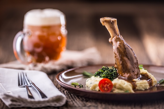 Lamb shank.Confit lamb shank with mashed potatoes spinach and draft beer in pub or restaurant.