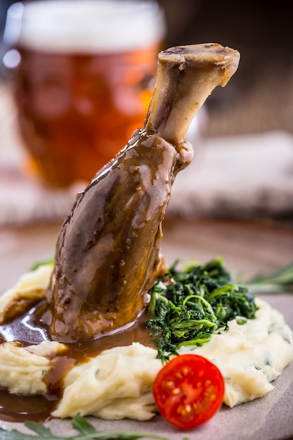 Lamb shank.Confit lamb shank with mashed potatoes spinach and draft beer in pub or restaurant.
