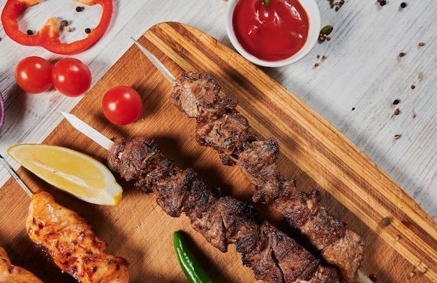 Photo lamb shish kebab with vegetables on a wooden board