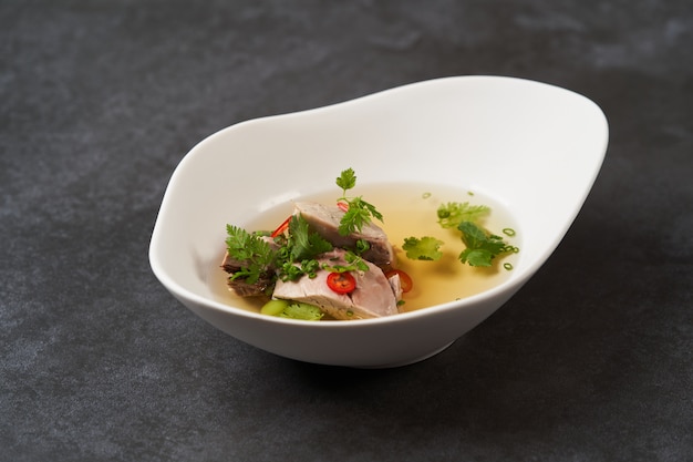 Lamb soup with chili pepper, tomatoes, parsley and beans in a white bowl