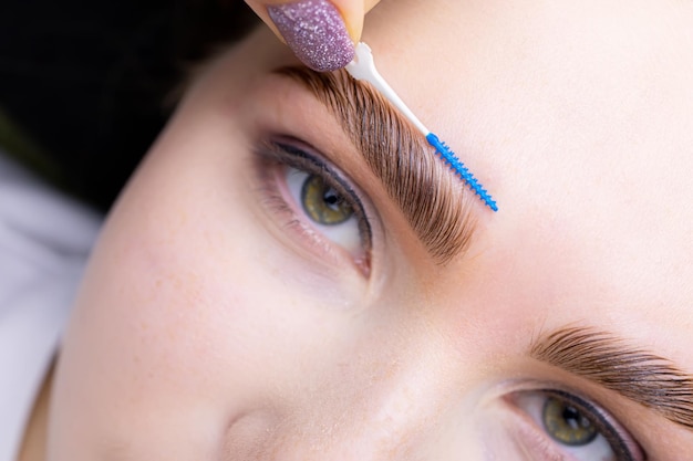 Lamination of eyebrows with the help of the composition, the master combs the eyebrow hairs at an angle of forty-five degrees