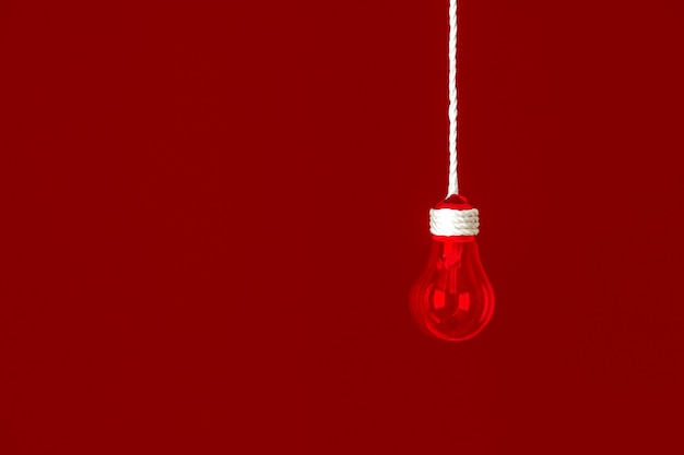 Lamp bulb hanging on the rope.  Red background. New idea concept.