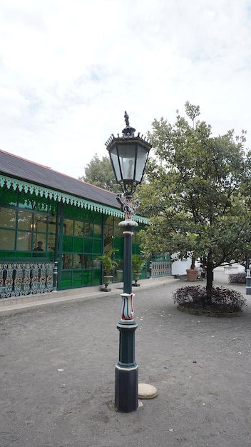 A lamp post in the middle of a park with a green building behind it.