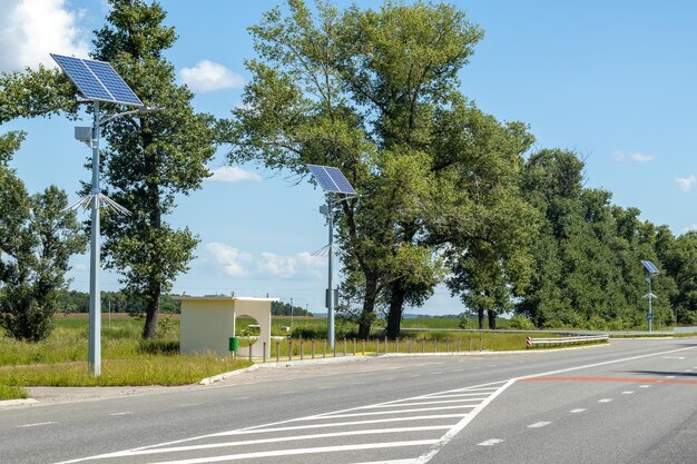 青空と木々のある道路に設置されたソーラー パネル システムを備えた街灯 ソーラー パネルを使用した自律型街路灯 太陽からのバッテリーを使用した街路灯