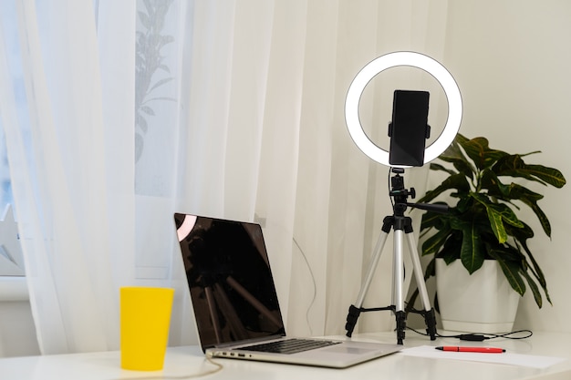 노트북 뒤에서 온라인 인터뷰를 위한 테이블 위의 램프와 삼각대