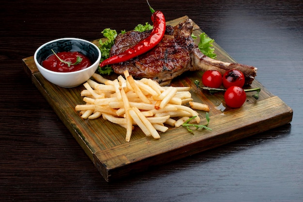 Lamsrack met friet en saus op een houten plank