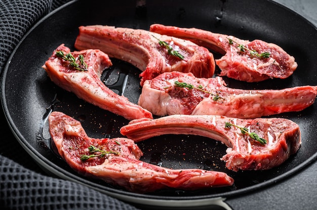 Lamsrack, rauw vlees met been. Biologisch lamsvlees. Zwarte achtergrond. Bovenaanzicht