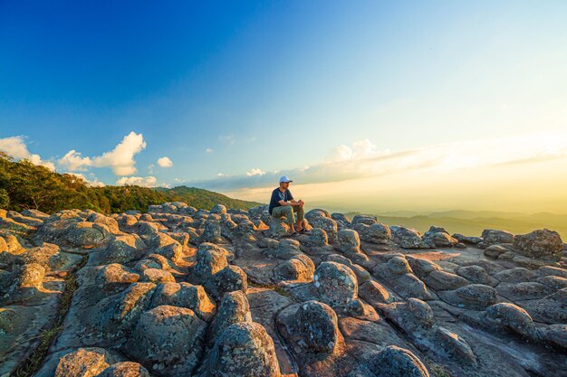 Lan Hin Pum National ParkMannelijke toerist en uitzicht op de bergenJonge man met rugzak zittend op rots