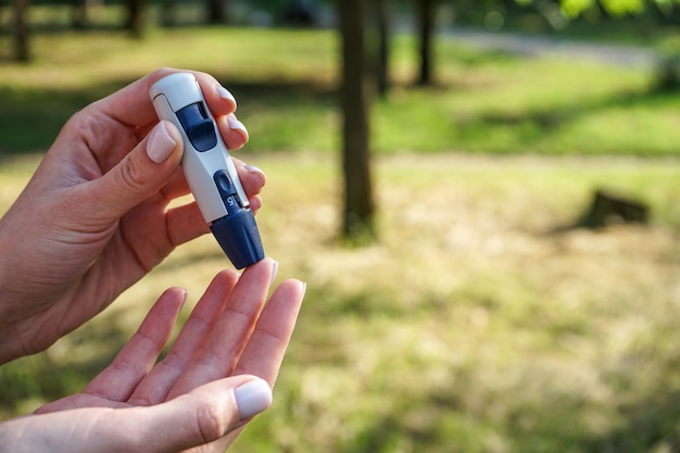 Lancet pen and glucometer in the hands of a woman in a street