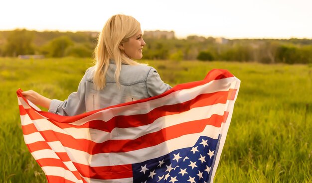 land, patriottisme, onafhankelijkheidsdag en mensen concept - gelukkig lachende jonge vrouw met nationale amerikaanse vlag op veld.