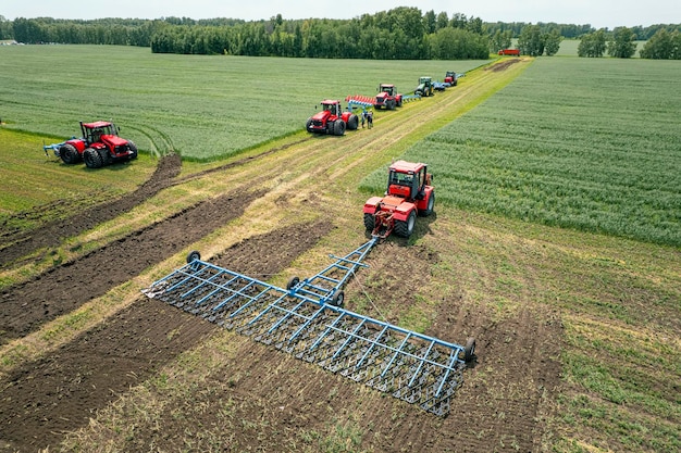 Landbouw machine oogst gewas in velden Trekker trekt een mechanisme voor hooien Oogsten in de herfst in de ochtend bij dageraad agribusiness in de regio Altai Rusland luchtfoto van bovenaf