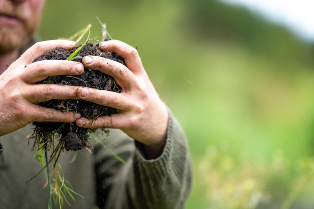 landbouwboer die grond in zijn hand houdt en compost voelt op een veld in Tasmanië Australië bodemwetenschapper in Australië bodemtest