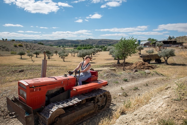 Landbouwersvrouw die een tractor op het gebied drijven