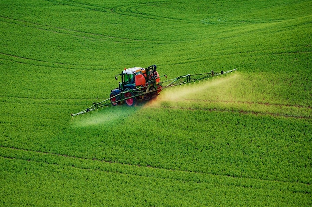 Landbouwmachines die insecticide naar het groene veld spuiten, agrarische natuurlijke seizoensgebonden lente-achtergrond