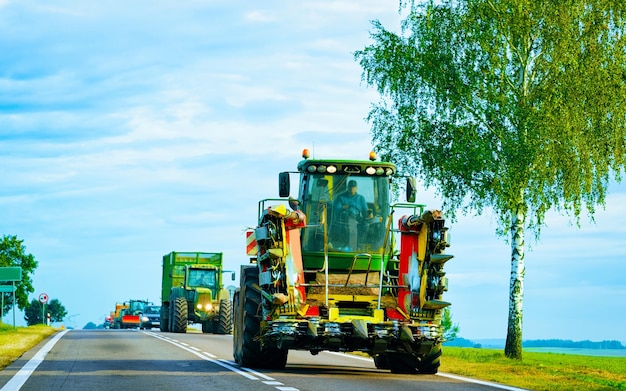 Landbouwtractor met aanhanger in de weg. De bestelwagen van het landbouwbedrijfvoertuig aan het werk op oprit. Europees vervoer. Platteland vervoer op de snelweg.