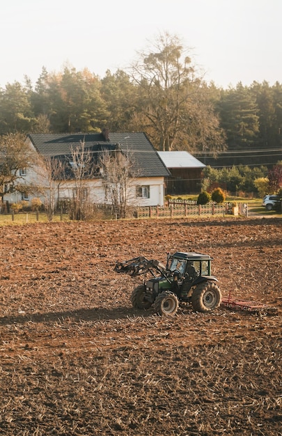 Landbouwtractor op het grondveld drukke landelijke landschapsboer die tijdens gouden uren werkt