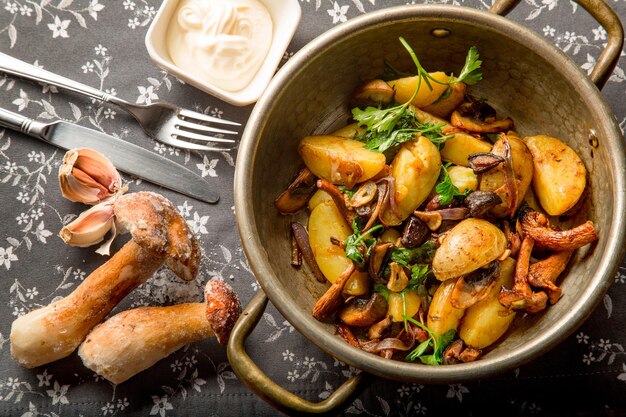 Landelijk gebakken aardappelen met uien en gestoofde champignons en kruiden. Serveren - bestek en decor. Concept - menu voor een restaurant. Uitzicht van boven