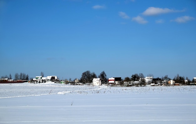 Landelijk landschap met een dorp aan de skyline na een sneeuwveld onder een heldere blauwe wolkenloze hemel