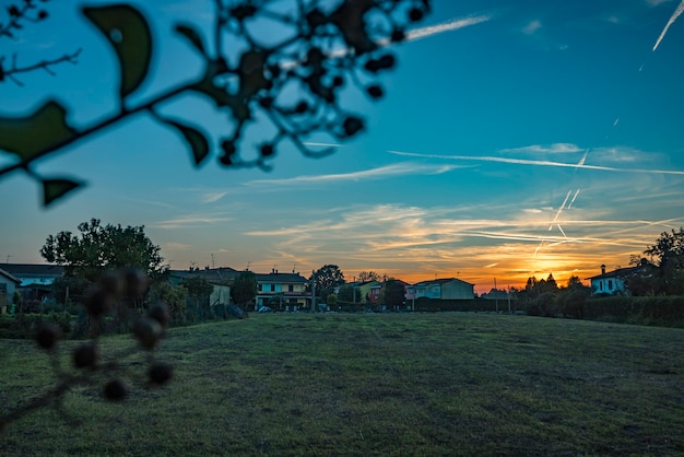 Landelijk landschap met prachtige gradiënt avondlucht bij zonsondergang. groen veld en dorp aan de horizon