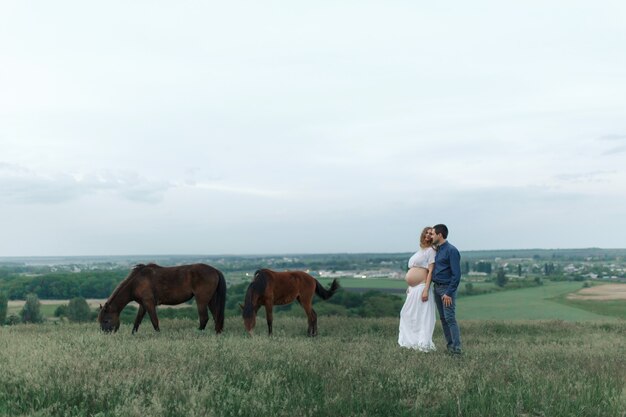 Landelijk paar op een groene weide communiceert met dieren. Zwangere vrouw. Therapie en ontspanning voor zwangere vrouwen.