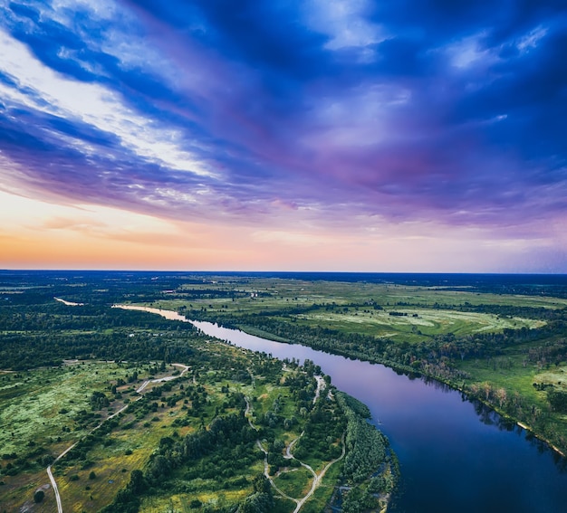 Landelijk zomerzonsonderganglandschap met rivier en dramatische kleurrijke lucht, natuurlijke achtergrond, luchtfoto