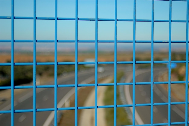 Landelijke weg gezien door een metalen hek