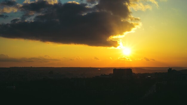 Landscape of amazing sunset over small city dramatic clouds golden sun