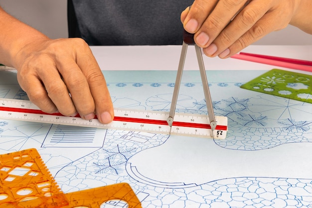 Landscape architect student use dividers and scale ruler on blueprint  in class.