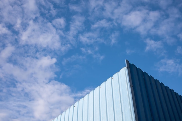 A landscape of a blue sky with light clouds. partially visible blue fence