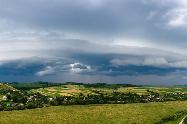 Landscape of dark clouds forming on stormy sky during\
thunderstorm over rural area