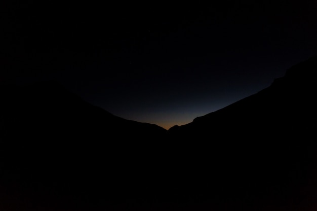 Landscape of the dark silhouette hill in the night with a light on them