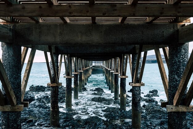 Foto paesaggio di un molo di legno sul mare in un luogo roccioso e bellissimo - nessuno sul posto e maltempo - lanzarote, isole canarie