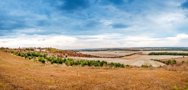 Landscape of farmland in autumn with colorful trees and dramatic sky