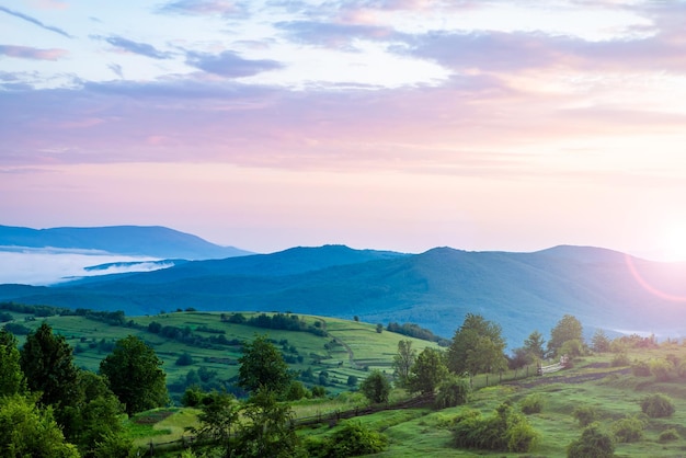 Landscape fog morning fog in the mountains thick fog over the\
mountains in the rays of the sun a beautiful sky green hills