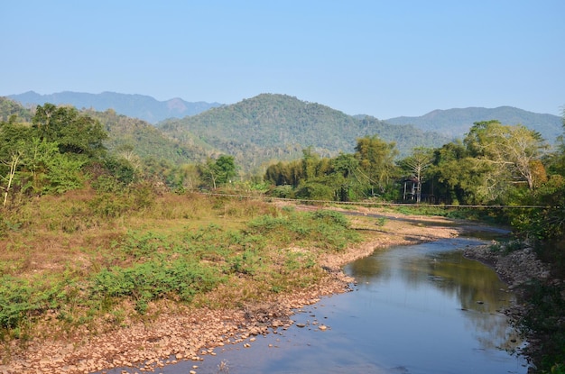 Пейзаж леса и горы с ручьем в утреннее время в деревне Бан Бо Клуа в районе Бо Клуа, Нан, Таиланд