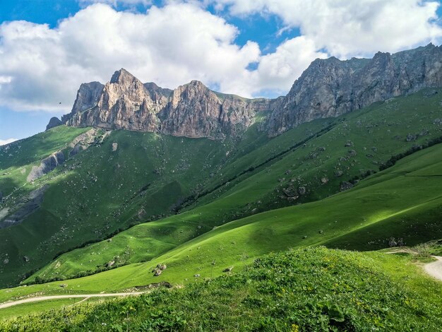 The landscape of the green Aktoprak pass in the Caucasus the road and the mountains under gray clouds Russia