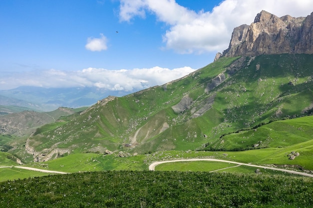 Il paesaggio del verde aktoprak passa nel caucaso la strada e le montagne sotto nuvole grigie