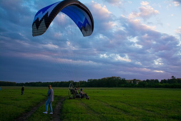 Landscape. green field and blue sky, in the background, in the distance are paragliders.