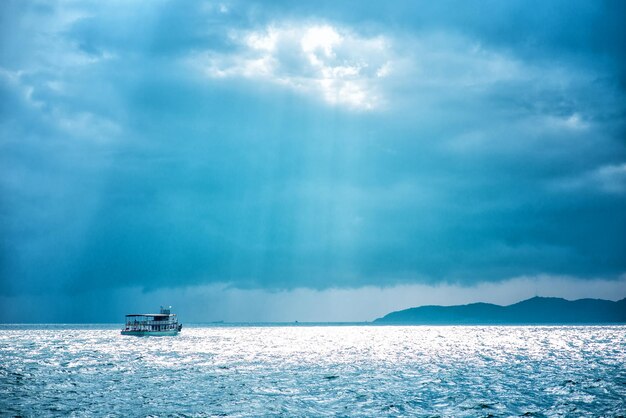 タイ湾の風景。美しい雲の切れ間からボートと島に太陽の光が降り注ぐ