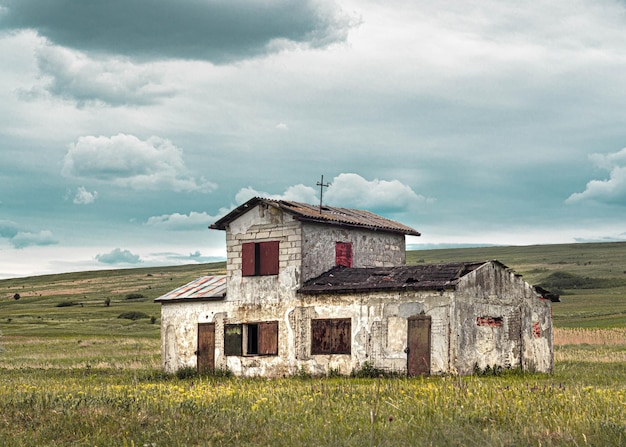 Landscape of house on field under blue sky with clouds.