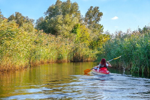 Immagine del paesaggio di una ragazza dai capelli rossi in una canoa