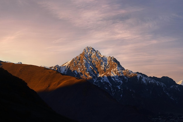 牧歌的な夕日のジョージア国の雄大な風光明媚な雪に覆われた茶色の山の尾根の風景