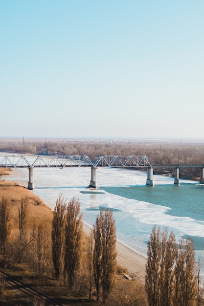 Paesaggio del ponte ferroviario su un fiume ghiacciato.