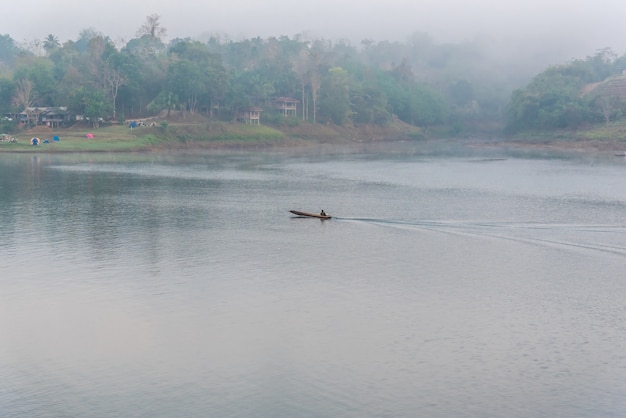 Landscape of river and long tail boat or houseboat with morning mist and coolness from predawn fog i