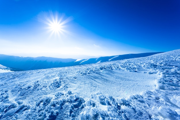 Landscape of snow winter valley and mountains and sun in above on clear winter frosty day. View of winter wonderland nature concept