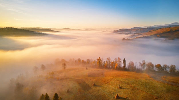 山の霧の谷の上の風景の日の出