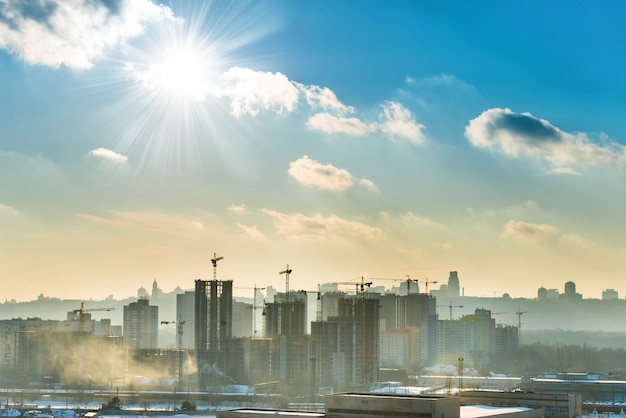 青い空、太陽、産業用クレーンで街の風景の夕日