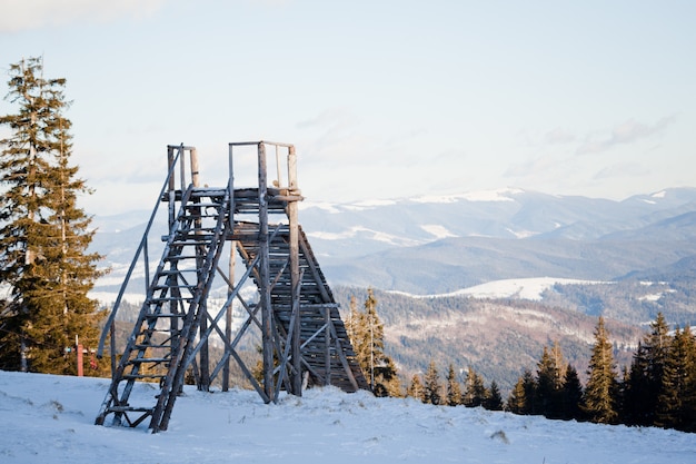 Landscape of sunset above coniferous winter forest and ski jump