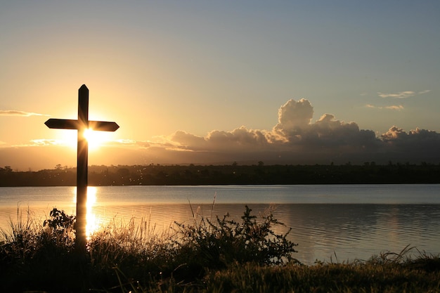 Landscape of a sunset on the lake with a cross